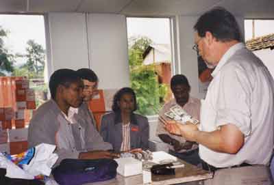 Åke Lönnberg from the IMF (right) shows samples of U.S. dollars and coins to central bank and postal staff in Timor Leste after the dollar was declared legal tender.
