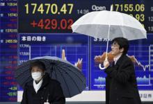 东京街头从股市显示牌前经过的行人：发达经济体低利率和负利率对保险公司构成风险（摄影：Frank Robichon/Corbis） 