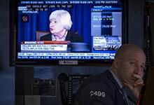 На заднем плане площадки Нью-Йоркской фондовой бирже идет трансляция пресс-конференции председателя ФРС Джанет Йеллен:  политика центрального банка в США стала возвращаться в нормальное состояние (фото: Brendan McDermid/Reuters). 
