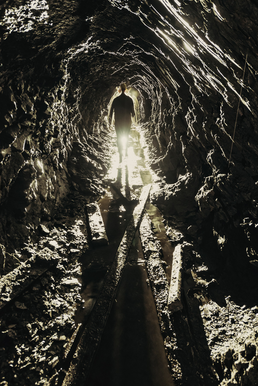 A gold miner is silhouetted in the narrow shaft of an abandoned gold mine in Colombia.