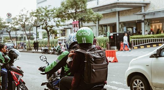Um condutor da Grab, uma startup de serviços eletrônicos de transporte da     Malásia, apanha um passageiro em Jacarta, na Indonésia: a digitalização     está transformando as empresas e os governos asiáticos (foto: Afif C.     Kusuma/iStock).