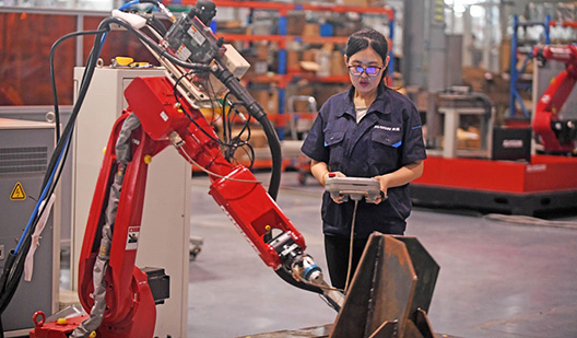 Uma engenheira ajusta o braço de um robô em uma fábrica robotizada em Shenyang, China, onde os robôs industriais são amplamente utilizados na manufatura (foto: Agência de Notícias Yang Qing Xinhua/Newscom).