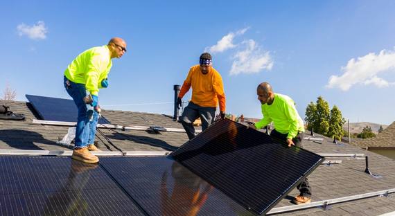 Image of three construction workers inspecting a solar panel