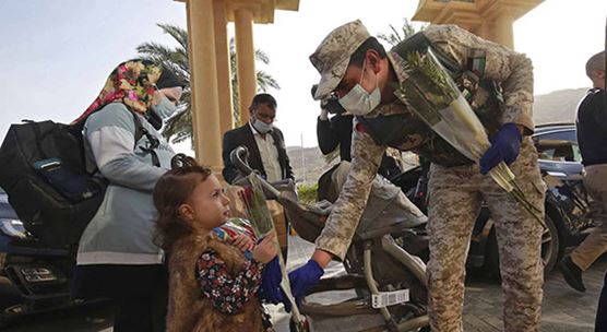 جندي أردني يقدم التحية والزهور للناس أثناء مغادرتهم أحد منتجعات البحر الميت حيث أمضوا فترة الحجر الصحي لمدة 14 يوما.  (الصورة: KHALIL MAZRAAWI/POOL/REUTERS)