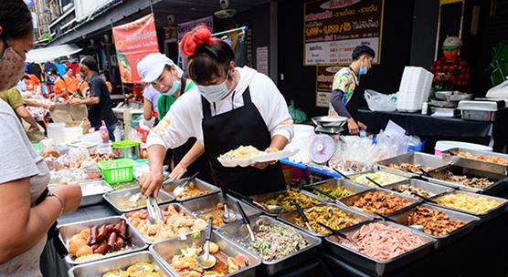 A Bangkok vendor serving food in a takeout box. Food services, accommodation, the arts, and entertainment have been hard hit by the COVID-19 economic downturn in Thailand. (photo: Brostock by Getty Images)