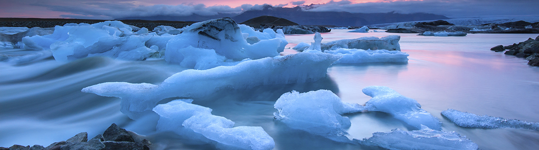 Icebergs floating in a glacier lake at sunset 