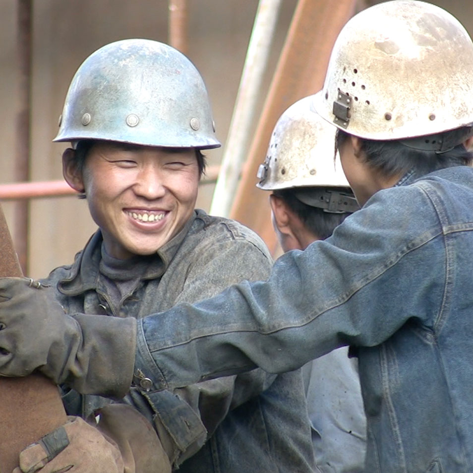 A construction worker smiling with coworkers at a work site