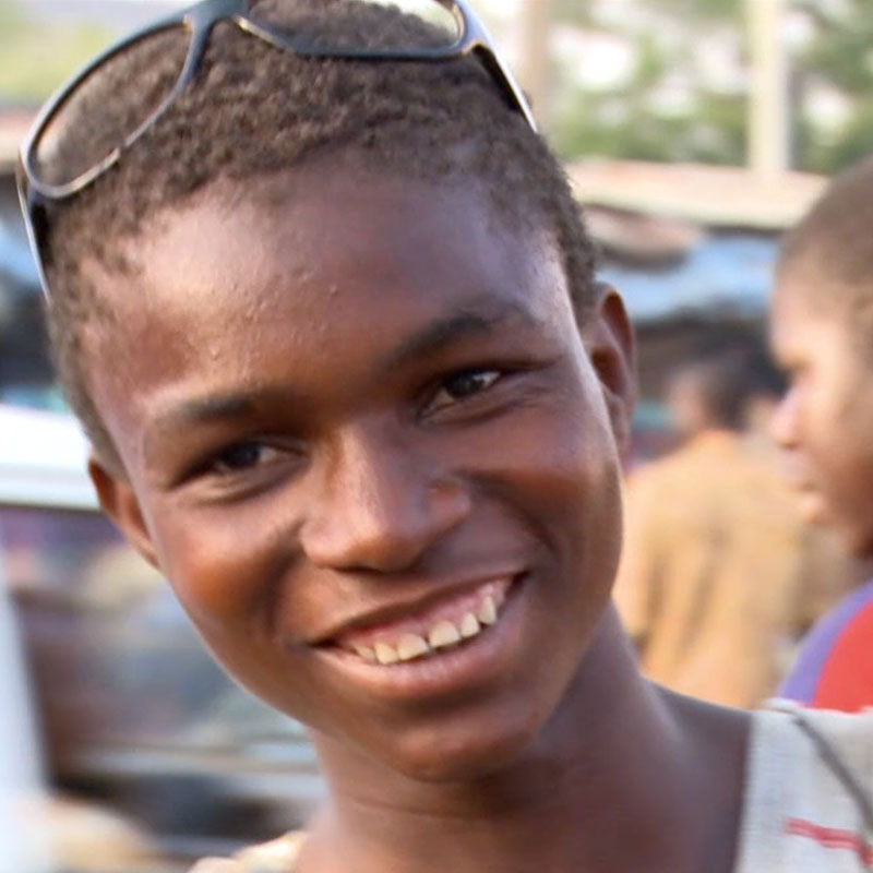 A person smiling in front of a busy street market