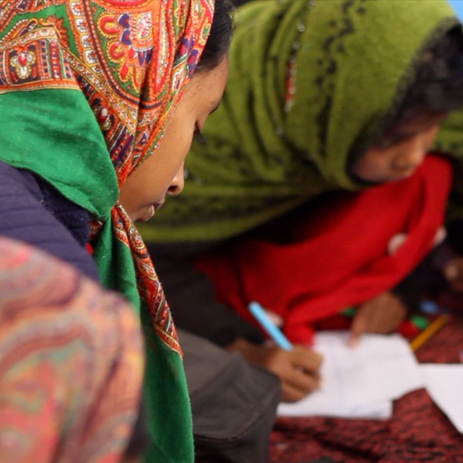 A group of young women sitting on the floor and writing