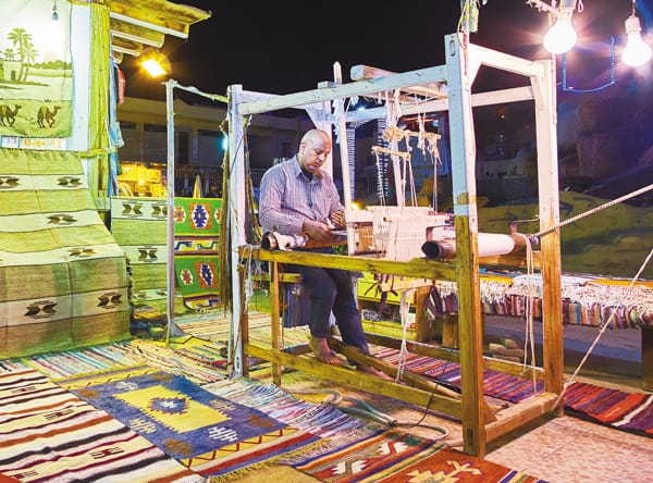 A man creating textiles on a loom at a night market