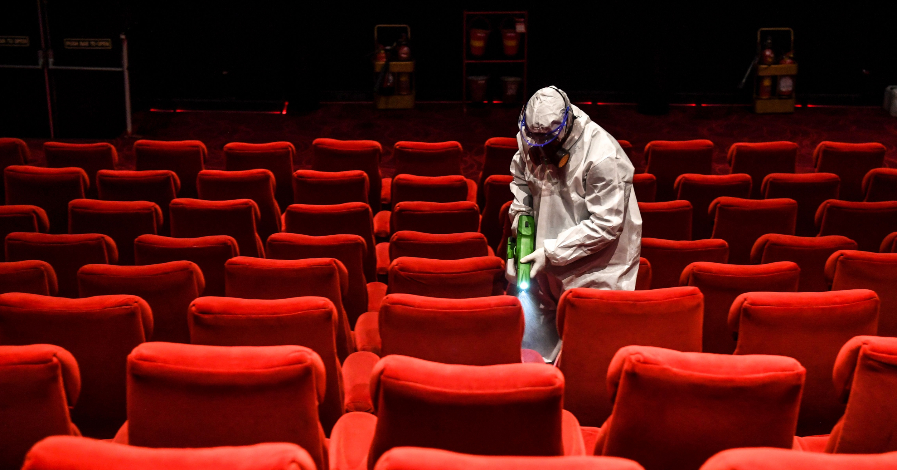 A worker in hazmat gear sanitizing a theatre