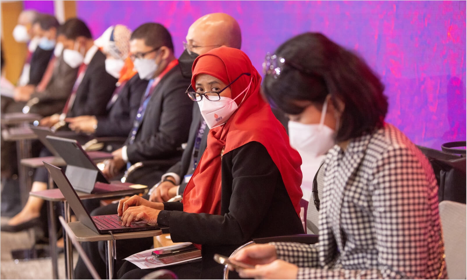 A woman in an orange-red hijab at a conference
