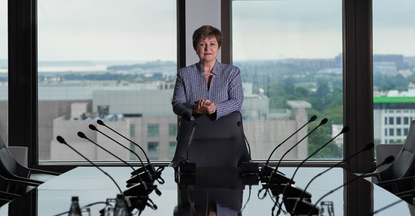IMF Managing Director Kristalina Georgieva standing at the head of a table in a meeting room.