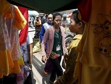 Garment workers walk past clothing stall in Cambodia.  The country’s robust garment exports have contributed to strong growth (photo: Corbis/Reuters/Samrang Pring) 